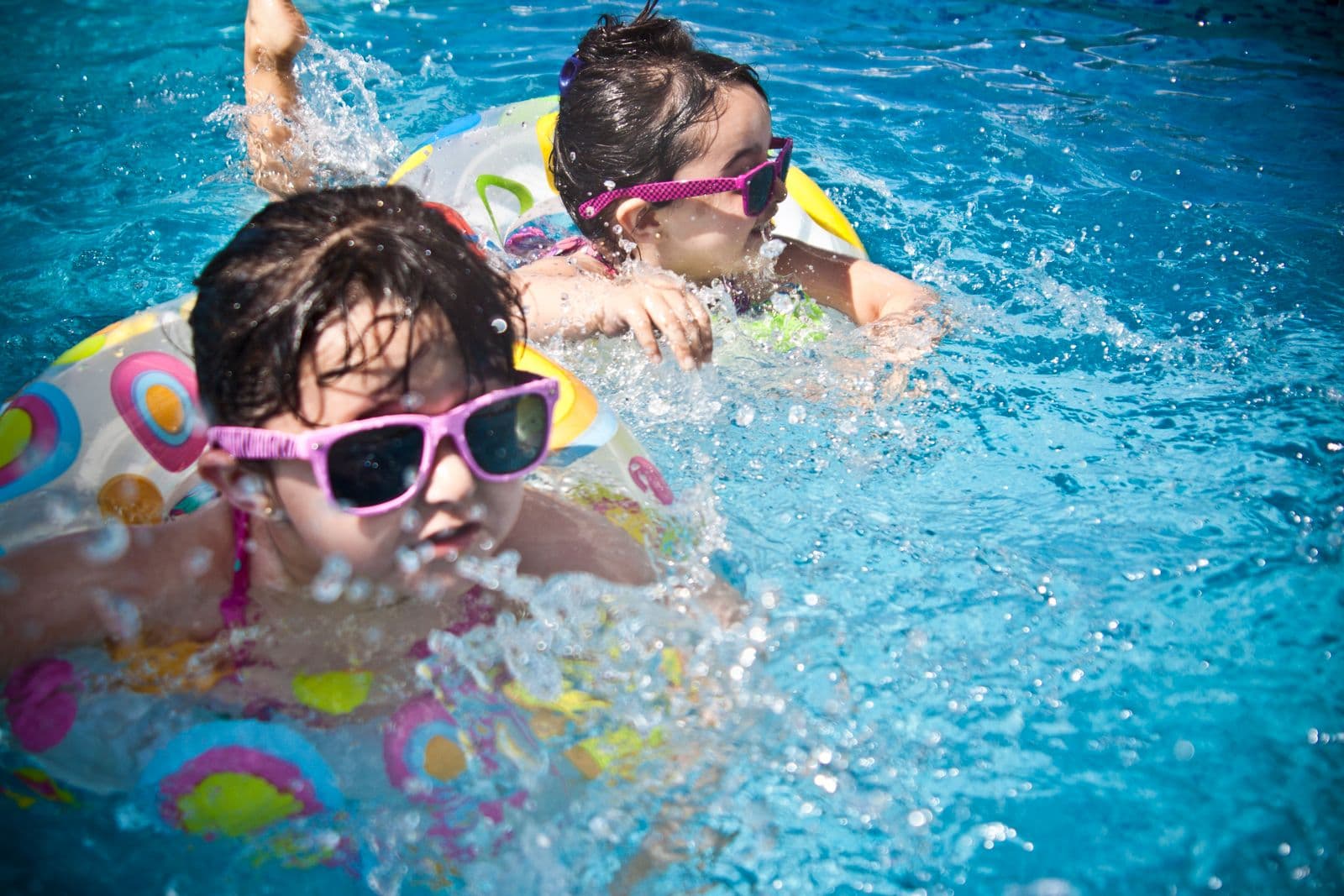 Two kids in sunglasses laughing on a pool float