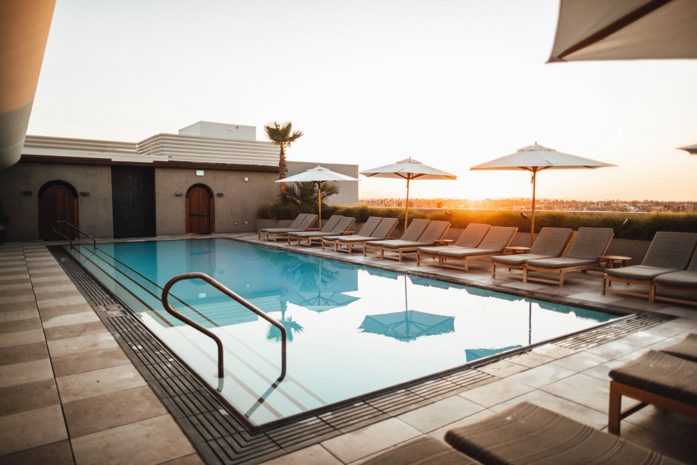 A backyard pool at golden hour with lounge chairs and umbrellas
